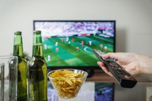 person watching football at home with drinks and chips