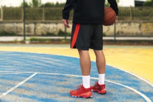 A basketball player with red shoes with the ball in his hand