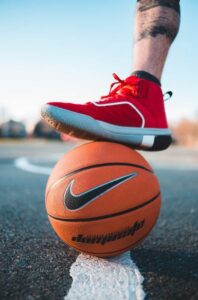 A man slightly steps on a basketball while wearing basketball shoes