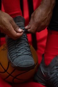 A man tying the shoelace of his basketball shoe