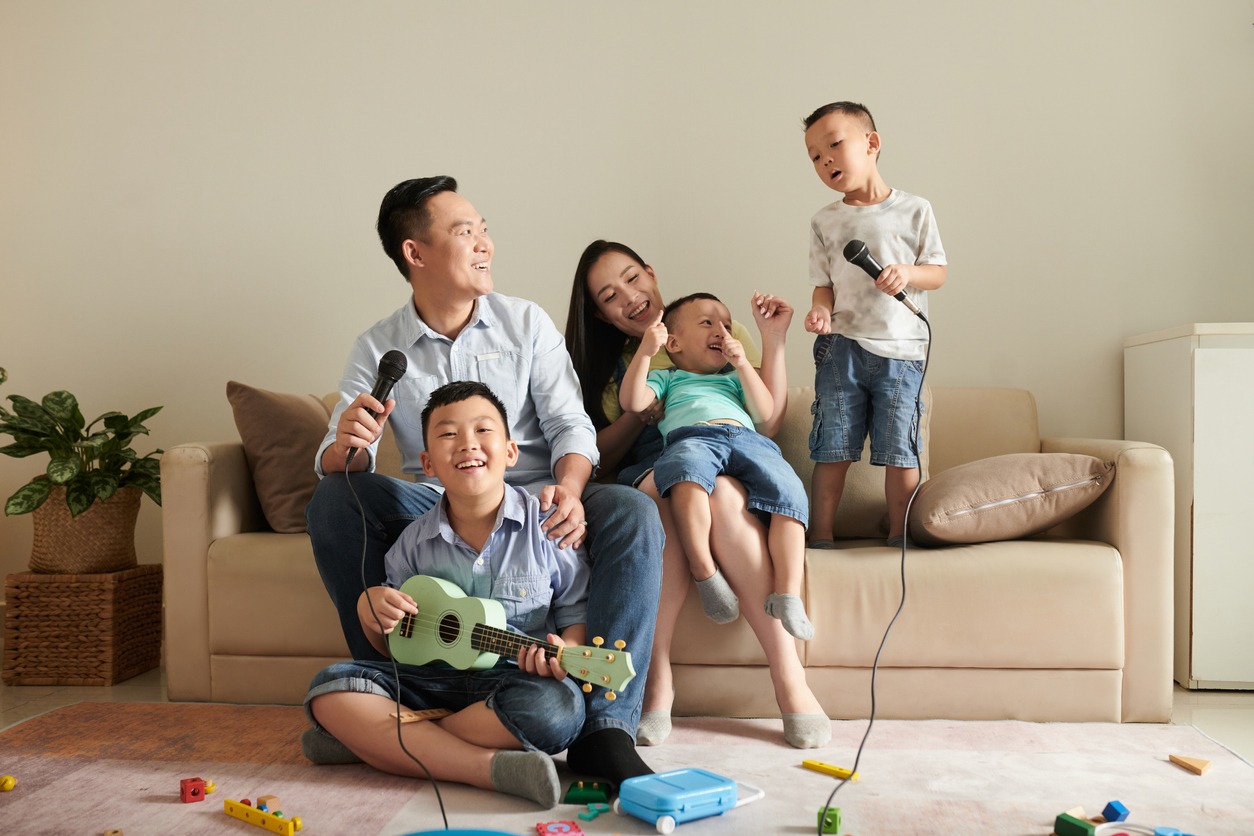 Happy-Asian-family-of-five-laughing-playing-ukulele-and-singing-song-into-microphone